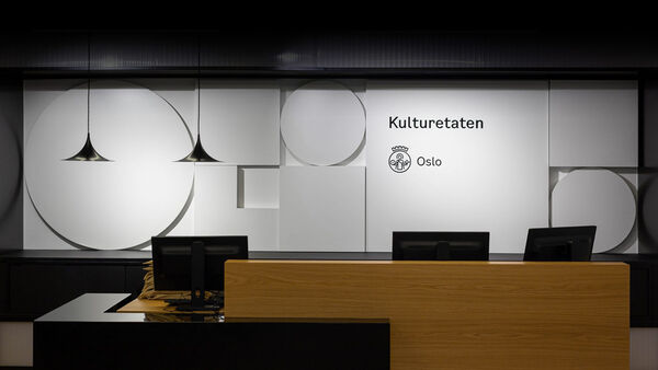 Resepsjon Kulturetaten, med moderne resepsjonspult i forgrunnen og Osloformer i hvitt på veggen bak.