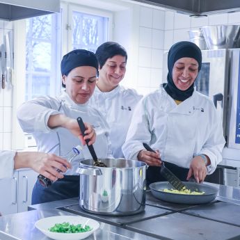 Tre kokker tilbereder et måltid.