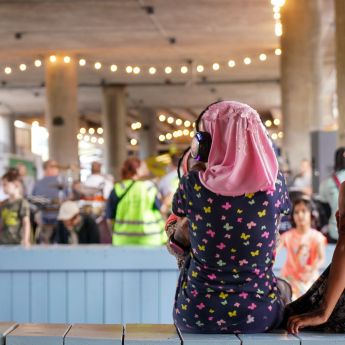 To jenter står under Olafiagangen, hvor det foregår et arrangement med mange mennesker.