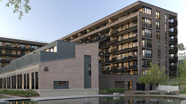 Teglsteinblokk i sju etasjer, med lavere blokk foran. Vannspeil i front.