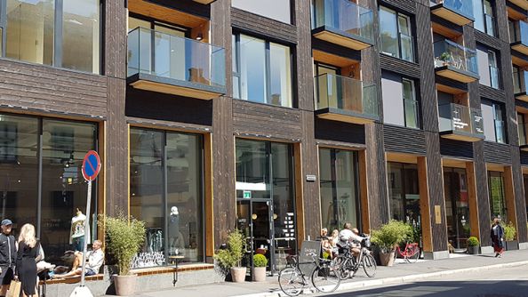 Blokk i bysentrum, næringslokaler med store vindusflater i første etasje, glassbalkonger i etasjene oppover