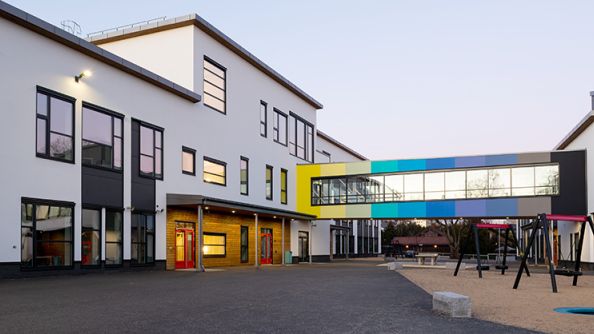To hvite skolebygg med en fargerik lukket bru mellom