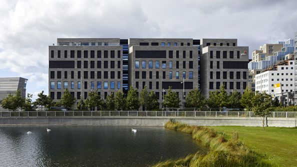 Stort kontorbygg med tre utspring, vannspeilet i middelalderparken i forgrunnen.