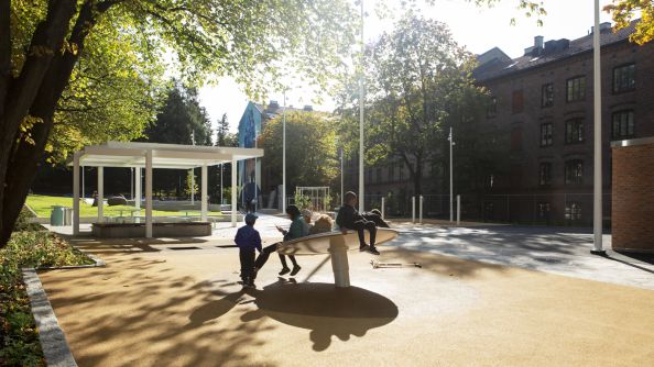 Barn på lekestativ. Lekestativet består av en stor skive.