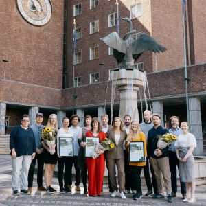 Mange mennesker foran Oslo rådhus med diplom og blomster
