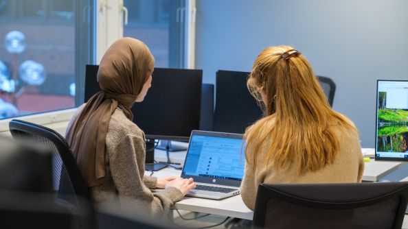 To kolleger samarbeider på en pc