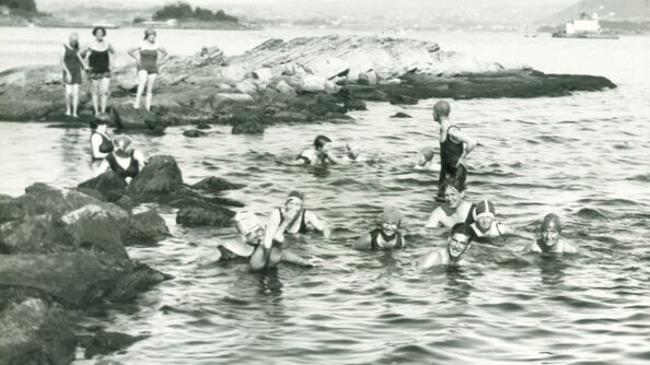 Et eldre fotogradi av mennesker som bader på Huk.