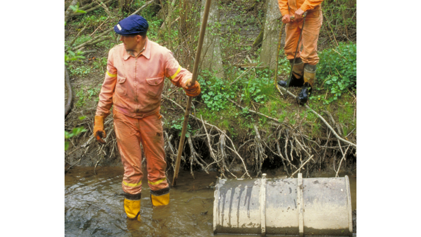 En mann som står med støvler i Akerselva for å rydde eleven.