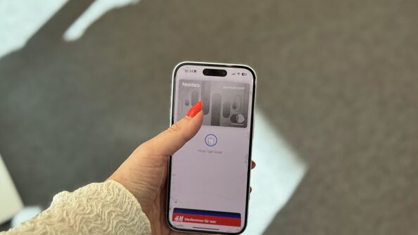 Hand holding iPhone with Nordea card showing in Apple pay