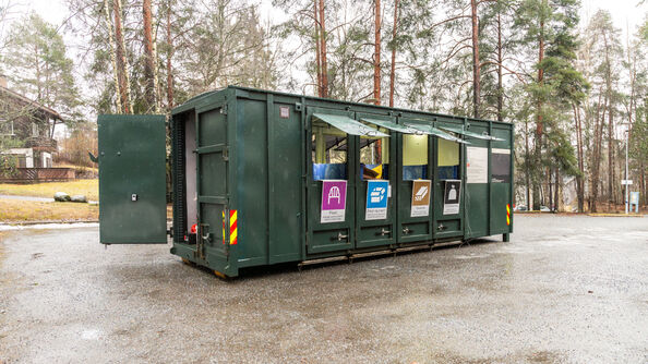 A photo of a green reycling box that has space for different items