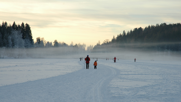 A photo of people walking and skiing on a frozen lake in Oslo in the winter