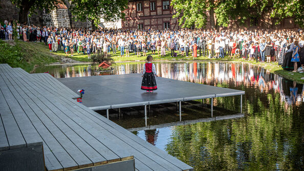 Little girl in Bunad at the 17 May Concert at Karpedammen with a large crowd. 