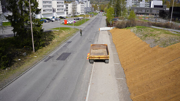 Anleggsområde langs vei, med lastebil parkert i kjørefelt og nysådd skråning på siden.