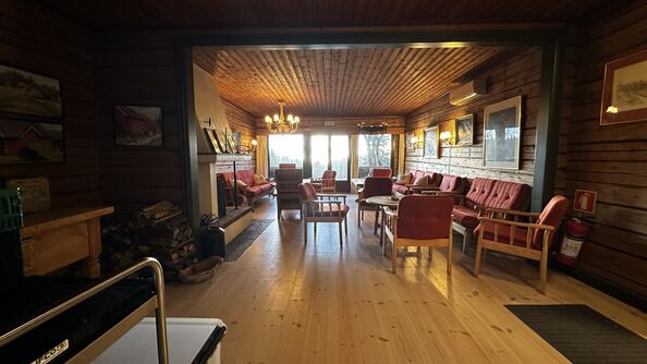 Peisestue med sittegrupper og utsikt mot skog.