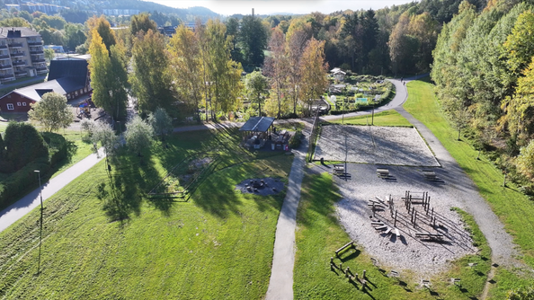 Flyfoto av park med stier, trær og lekeområde. Området har sitteplasser, sandflate og åpne gressområder.