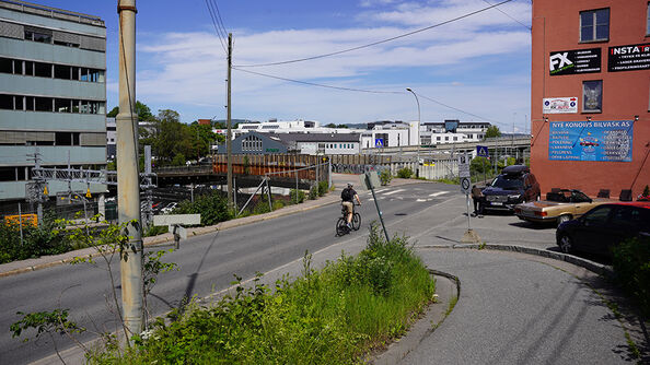 Gateområde med syklist og jernbanebro i bakgrunnen.