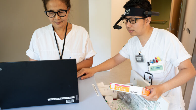 To sykepleiere står på et pasientrom og går gjennom utstyr til digital konsultasjon i forbindelse med sårbehandling.