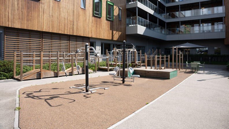 Et helsehusbygg med utvendig treningspark og hinderløype til rehabilitering for pasienter på helsehuset.
