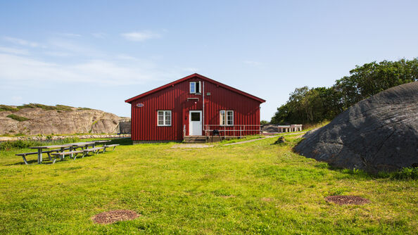 Kinsbakken feriesteds røde fasade med svaberg og grønn gressplen i forgrunnen