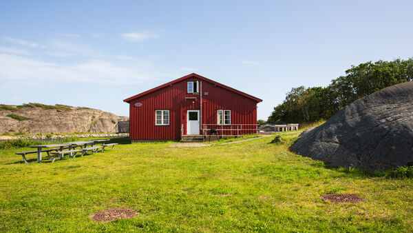 Kinsbakken feriesteds røde fasade med svaberg og grønn gressplen i forgrunnen