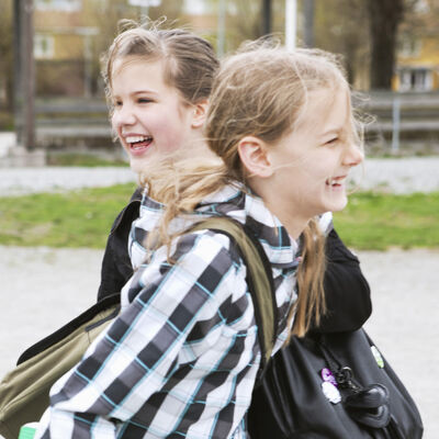 To skoleelever med ryggsekker utendørs.