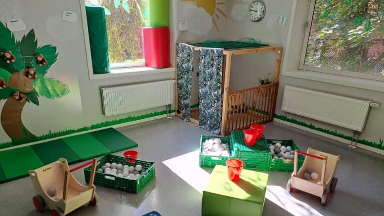 Lekeområde innendørs med veggmaleri, to vinduer og et utvalg leker 