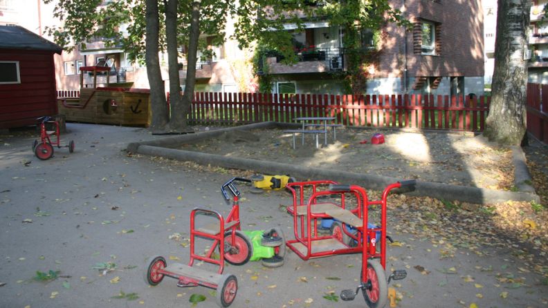 Uteområde med sandkasse og trehjulssykler med tær rundt