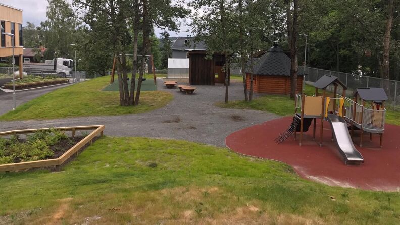 Stort uteområde som er delt inn i flere soner med klatrestativ, husker og benker 