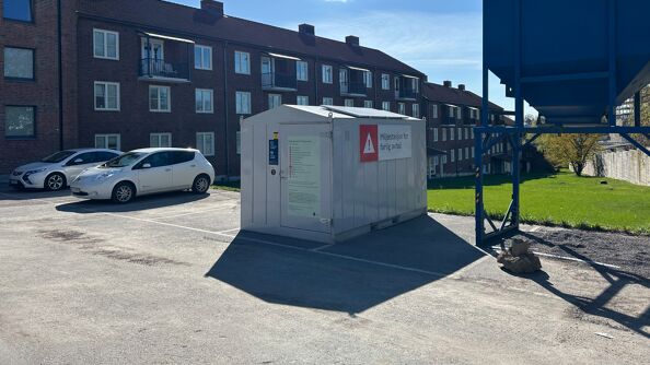 Grå container foran brunt murbygg