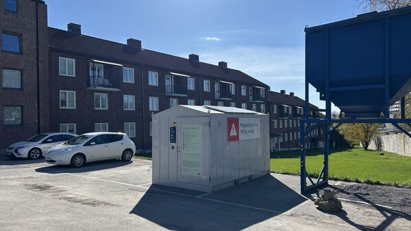 Grå container foran brunt murbygg